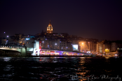 Galata Bridge illuminated by restaurants on the lower level and protected by Galata Tower in the distance.
